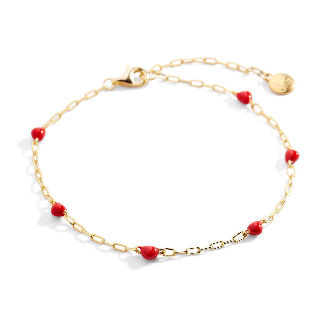 Gold bracelet with red beads on a white background
