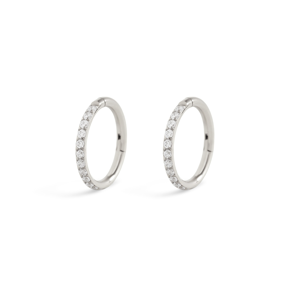 Pair of silver hoop earrings with small stones on a light gray background
