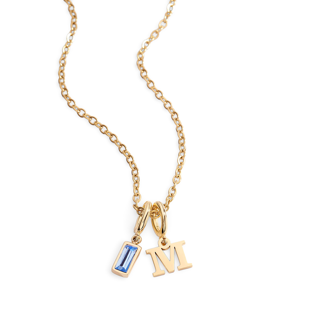 Gold necklace with a blue gemstone pendant and 'M' letter charm on a light gray background