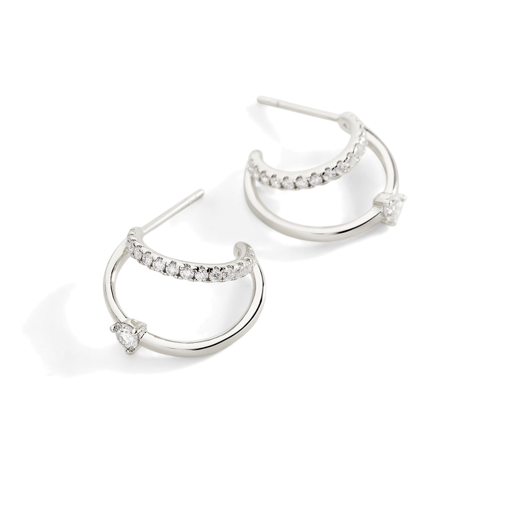 Silver hoop earrings with embedded stones on a light gray background