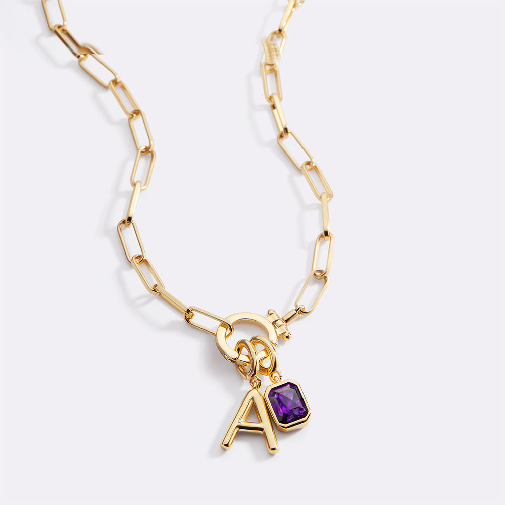 Gold necklace with a purple gemstone and letter 'A' charm on a white background