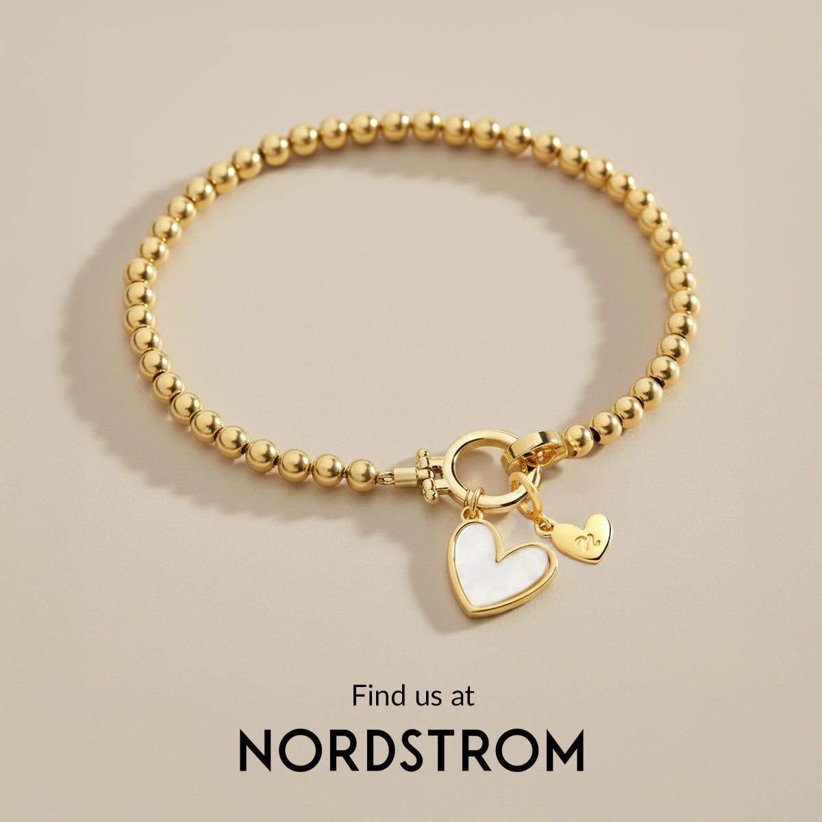 Gold beaded bracelet with a heart charm on a beige background, Nordstrom branding visible.