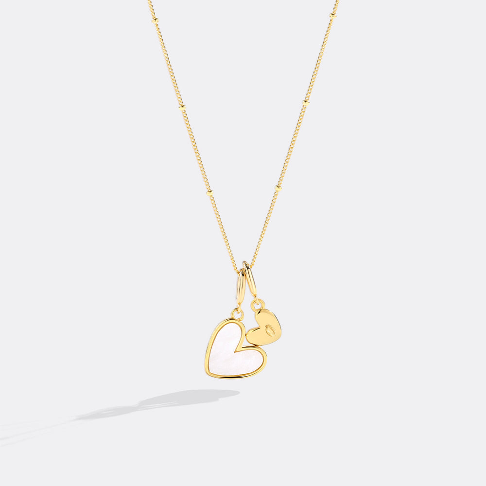 Gold heart-shaped pendant necklace on a light gray background