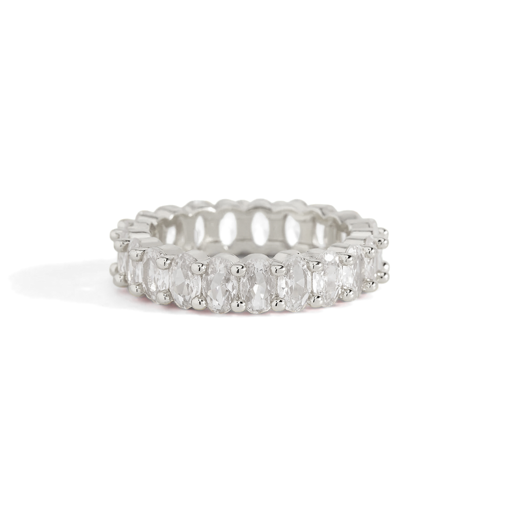 A gold-colored eternity ring with oval-shaped stones set around its entire circumference.