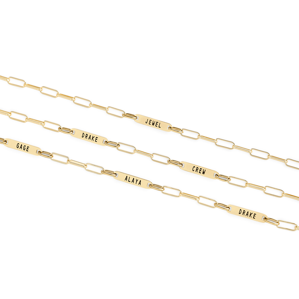 Gold paperclip chain necklaces with engraved names on a white background