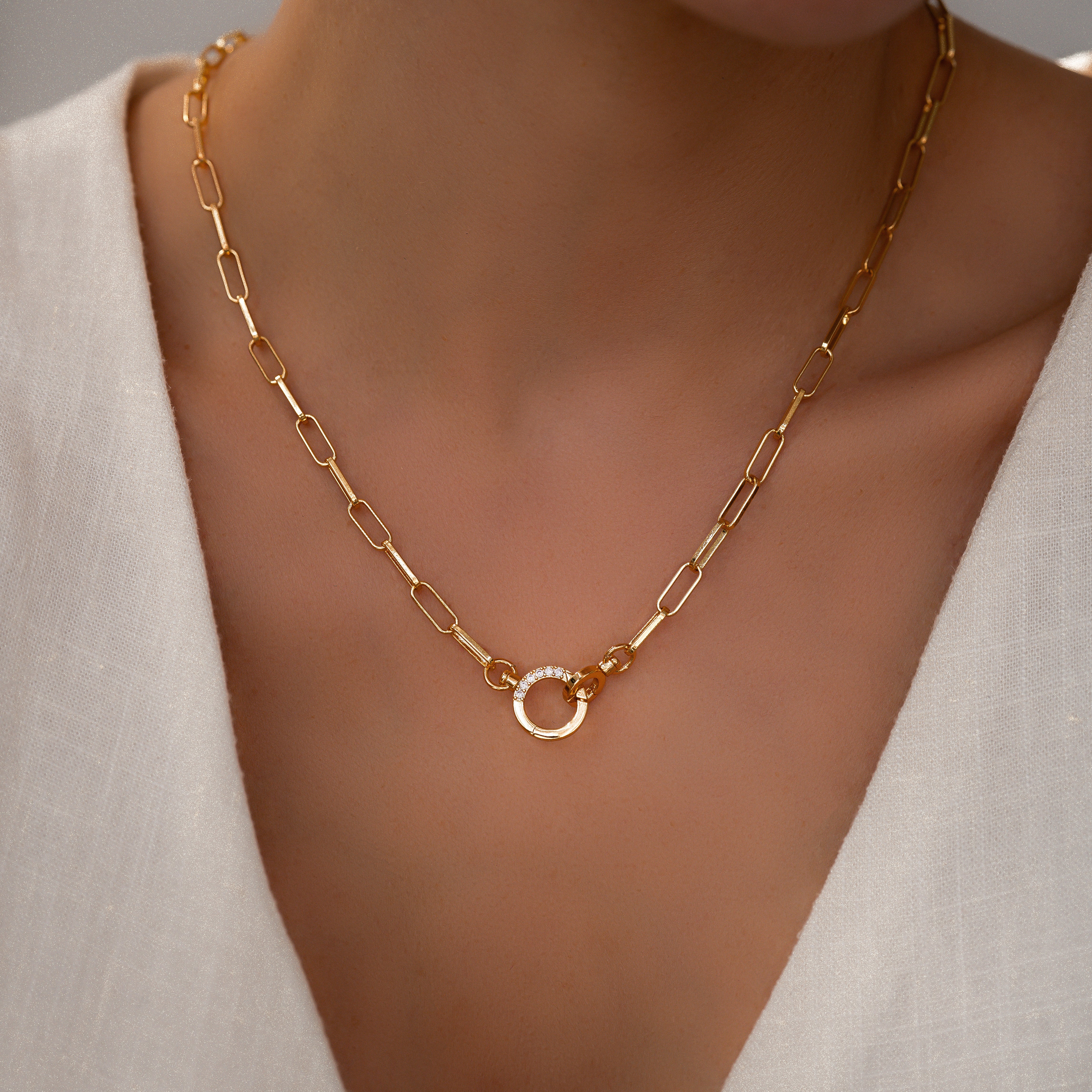 Gold necklace with a heart-shaped clasp on a mannequin neck.