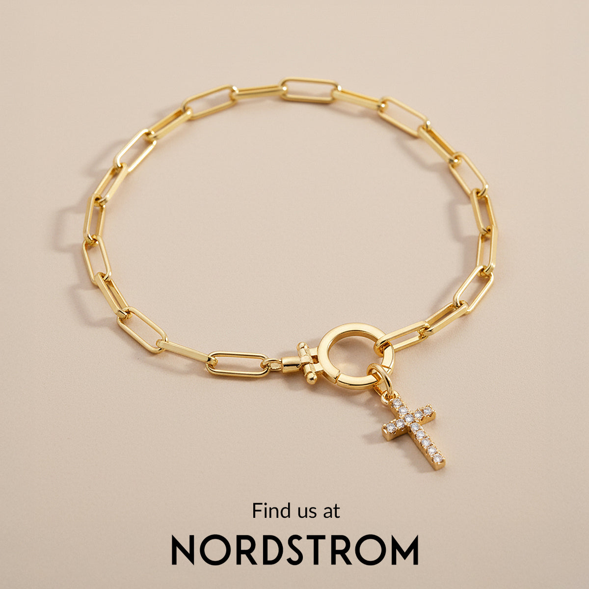 Gold bracelet with a cross charm on a beige background, Nordstrom branding visible.