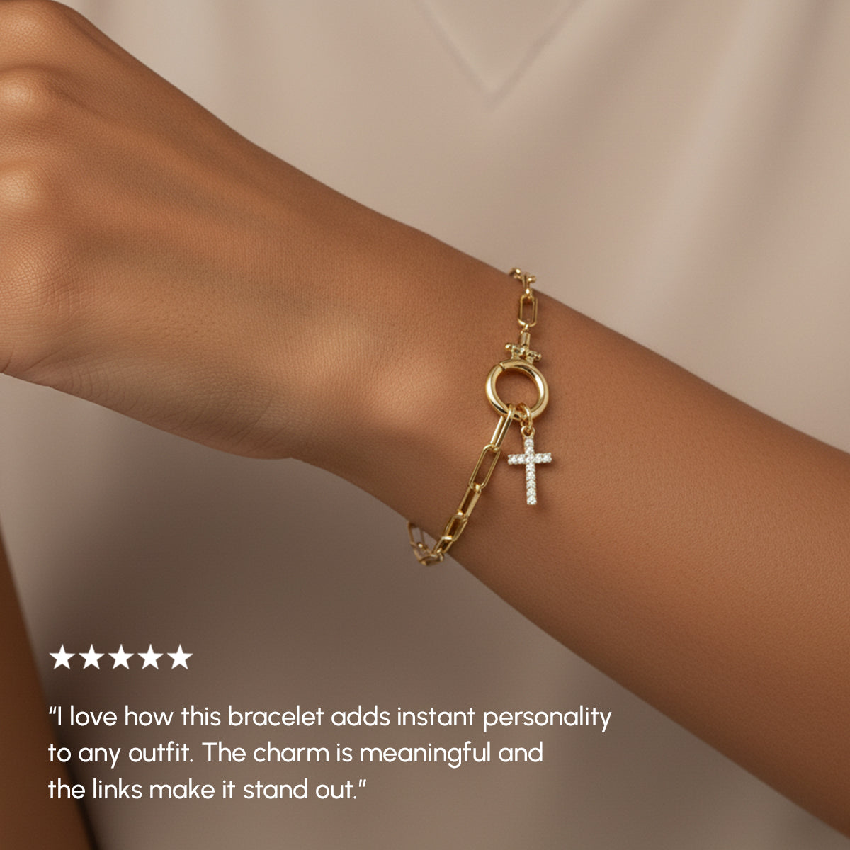 Gold bracelet with charms on a wrist against a neutral background