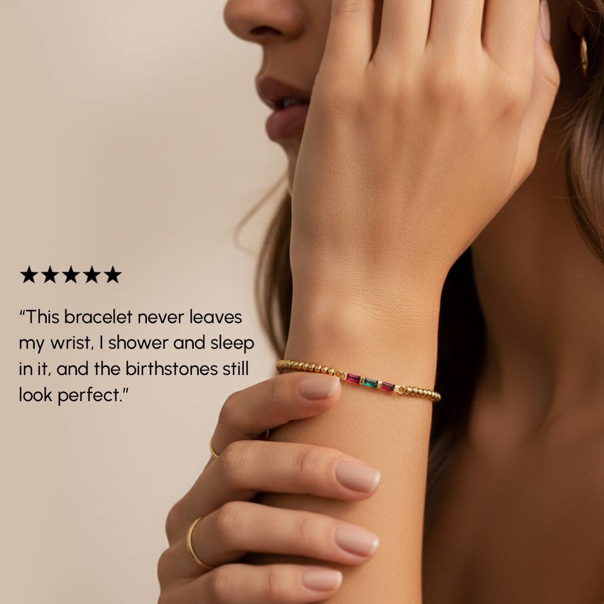 Woman wearing a gold bracelet with birthstones on a beige background