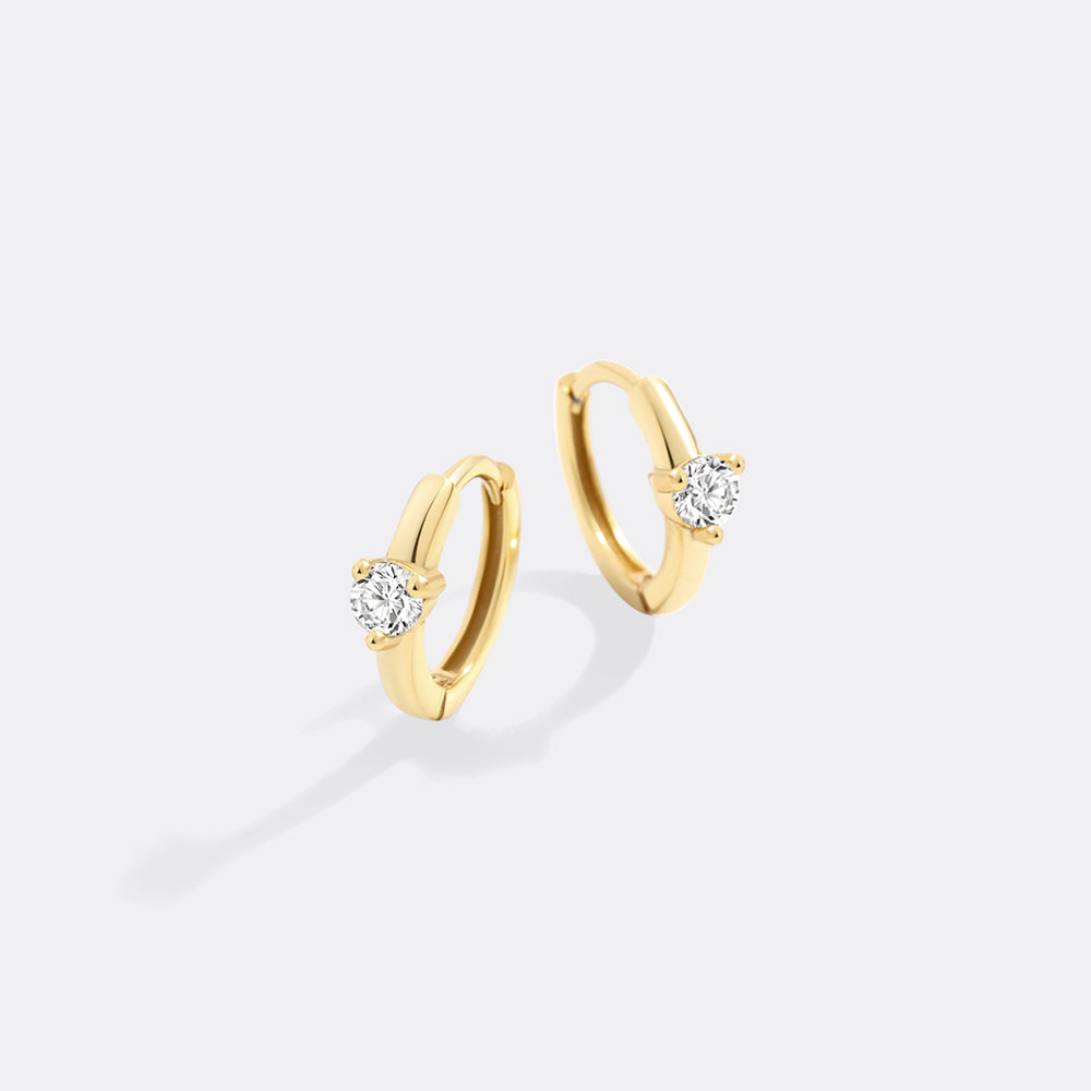 Gold hoop earrings with small diamonds on a light gray background