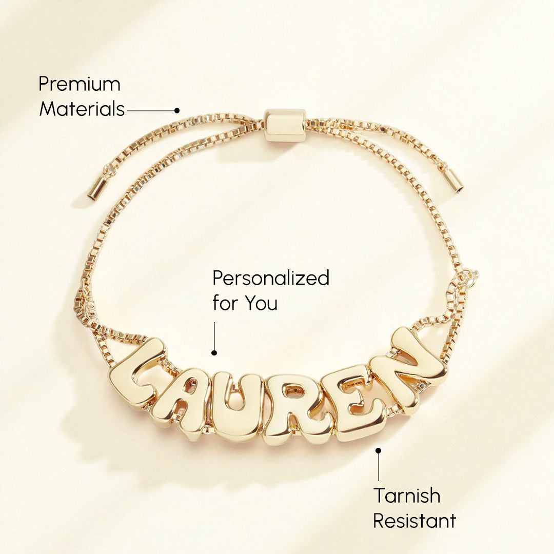 Gold bracelet with 'LAUREN' on a beige background