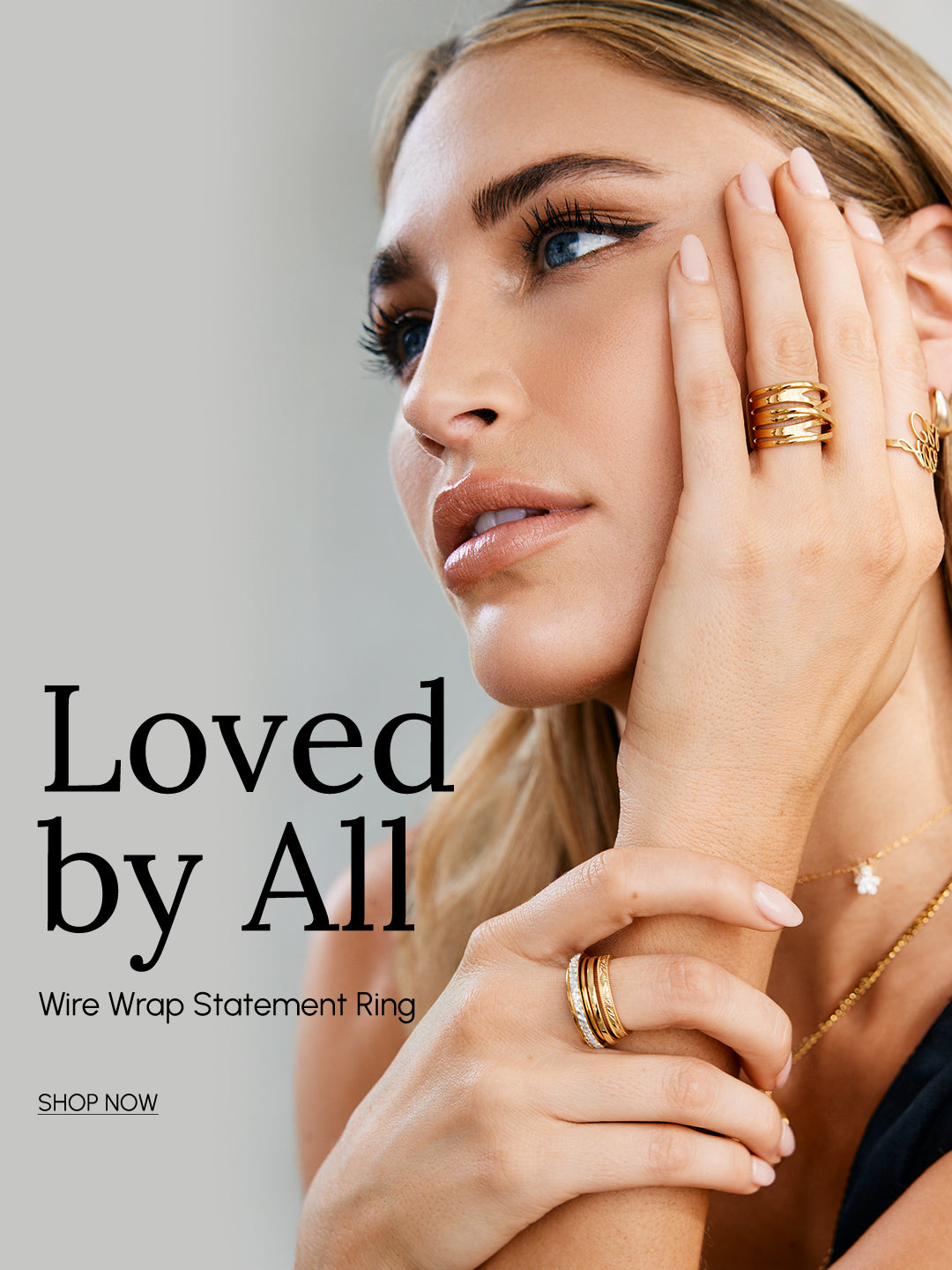 Woman wearing gold wire wrap statement rings with text 'Loved by All' on a gray background
