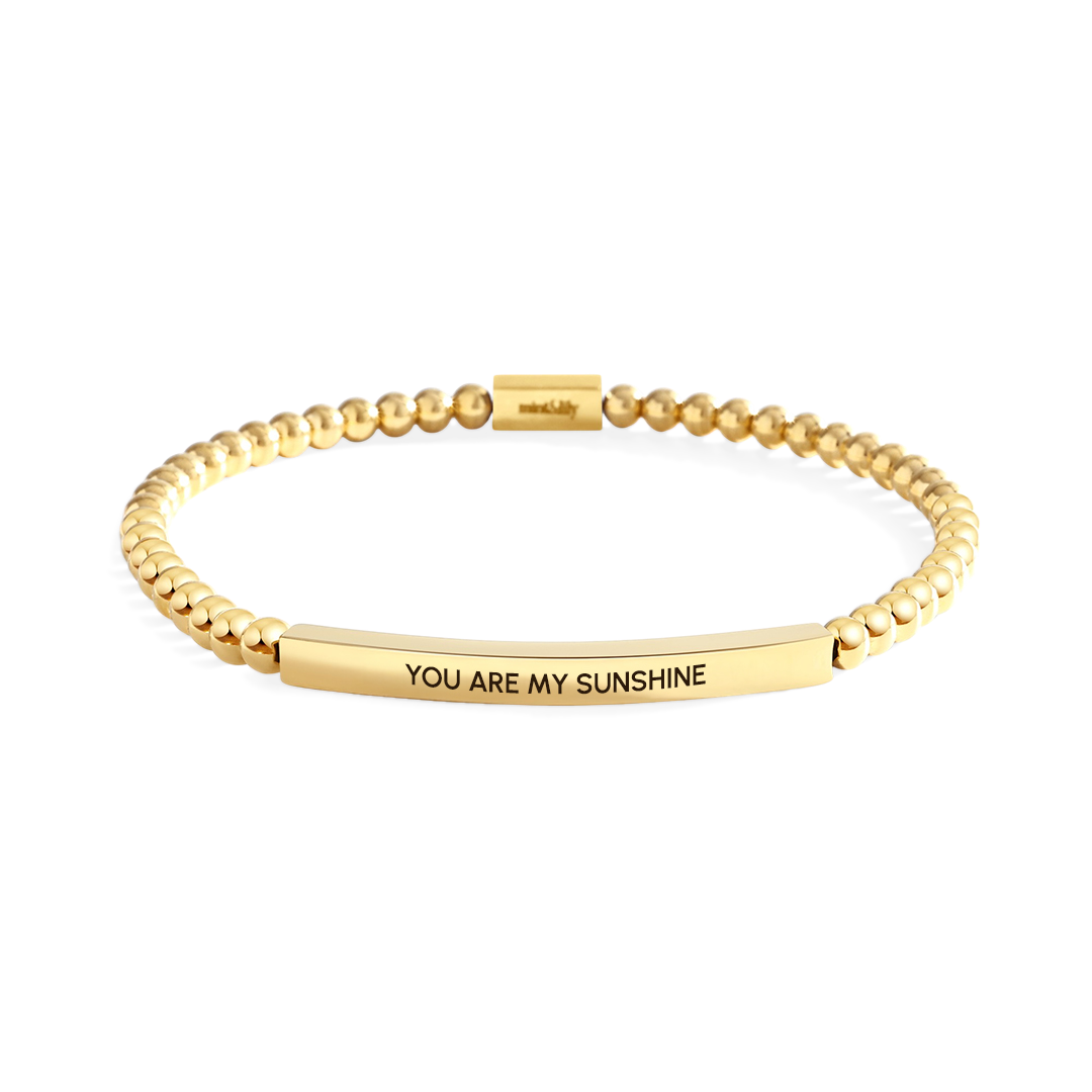 Gold bracelet with 'YOU ARE MY SUNSHINE' engraving on a white background