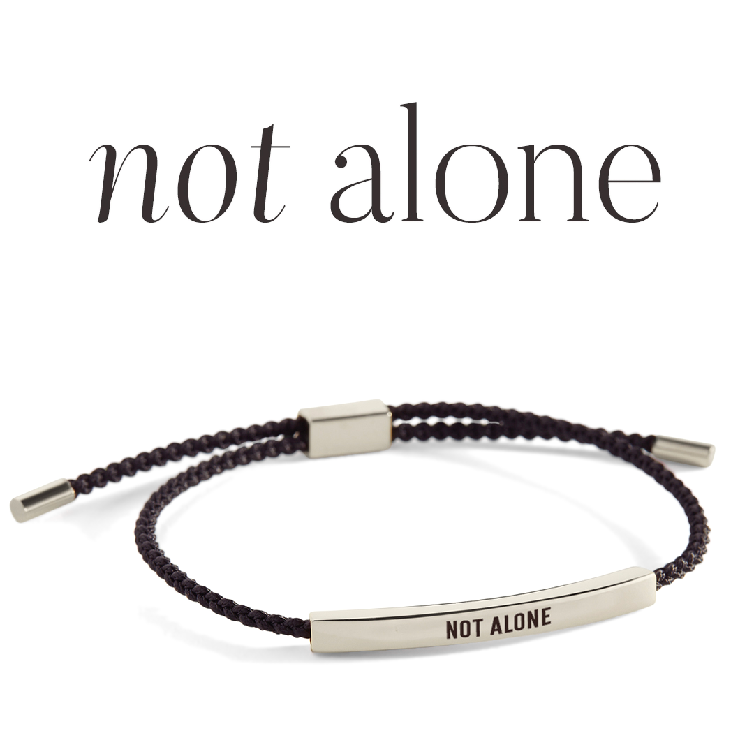 Bracelet with 'NOT ALONE' engraving on a light gray background