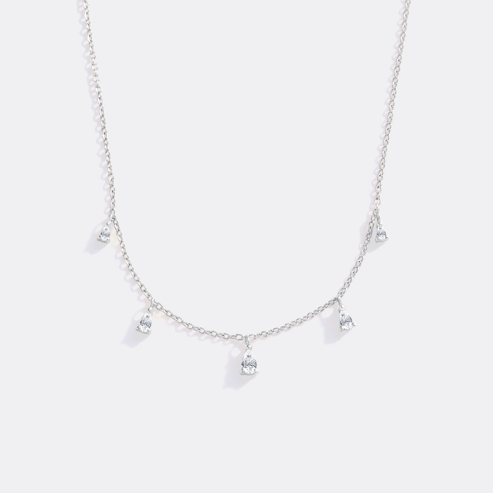 Silver necklace with heart-shaped pendants on a light gray background