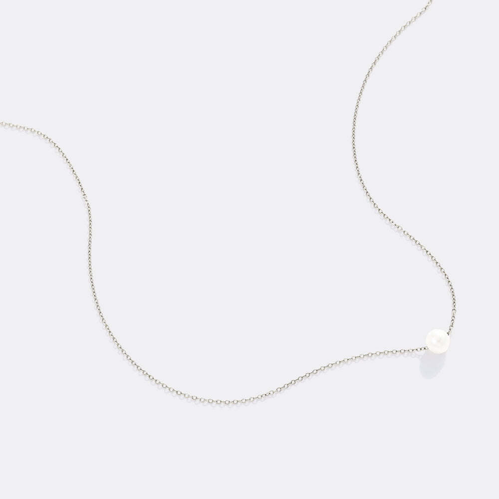 Delicate silver necklace with a small heart pendant on a light gray background