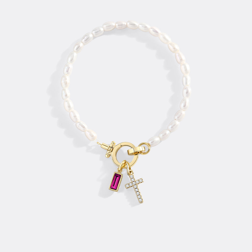 Pearl bracelet with gold clasp and charms on a white background