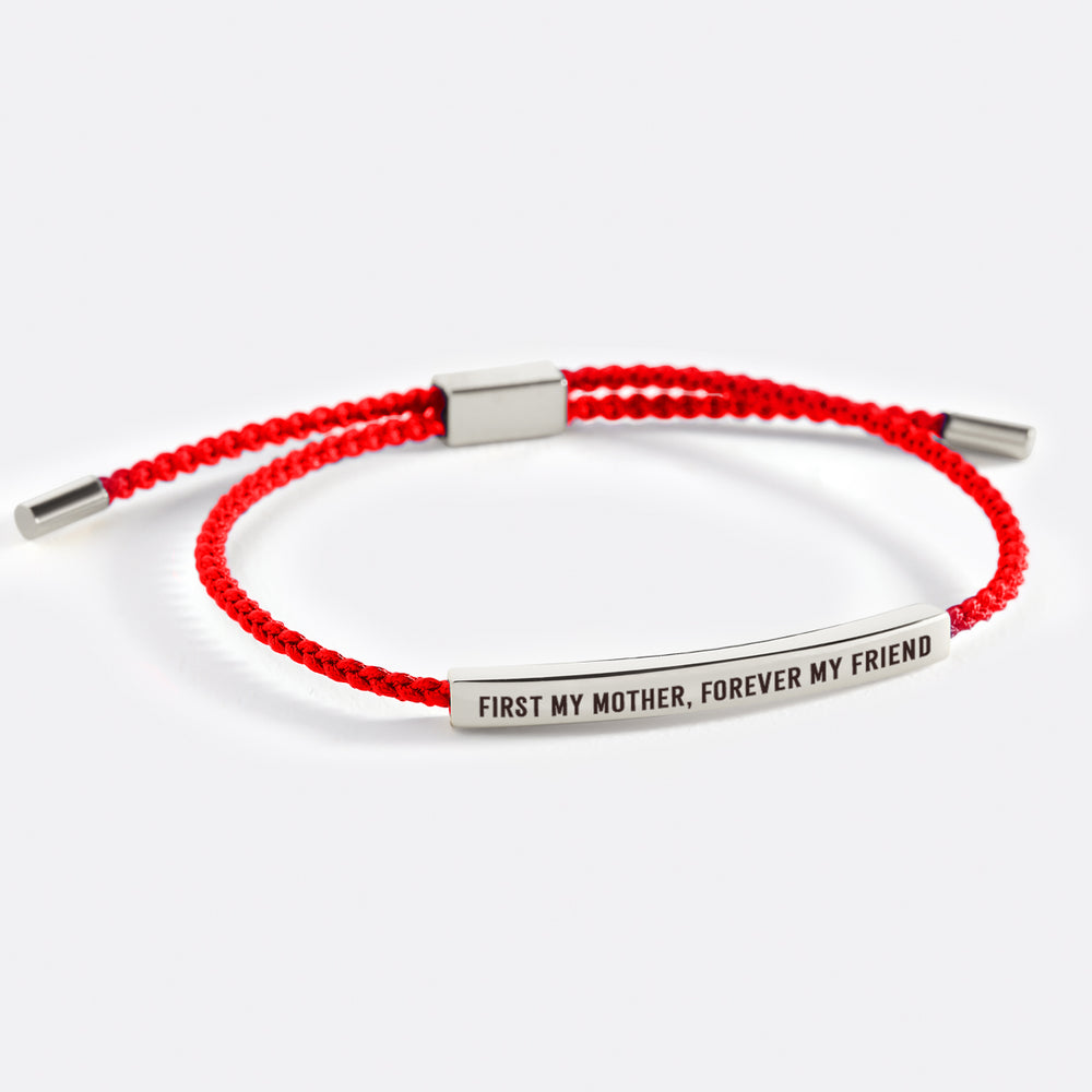 A dark-colored bracelet with metal accents and an inscription that reads 'first my mother, forever my friend'.