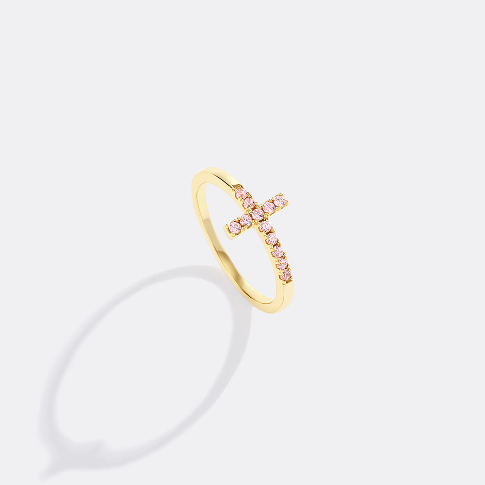 Gold ring with pink gemstones on a light gray background
