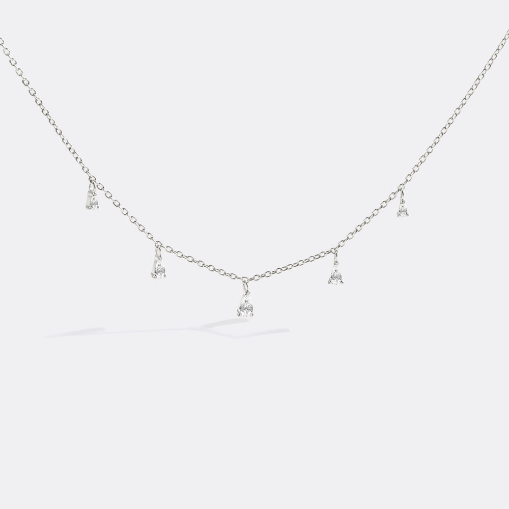 Silver necklace with small pendants on a light gray background