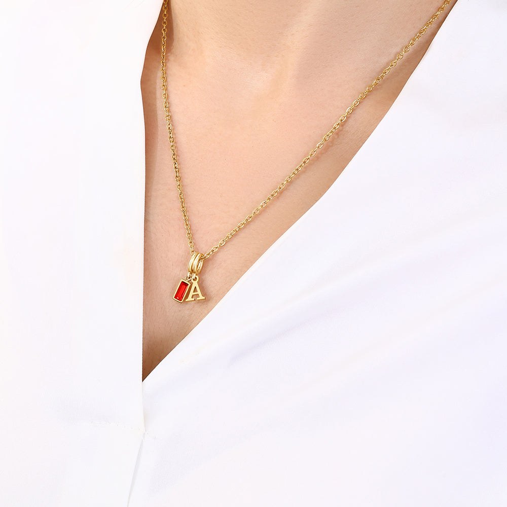 Gold necklace with a red and gold pendant on a white background