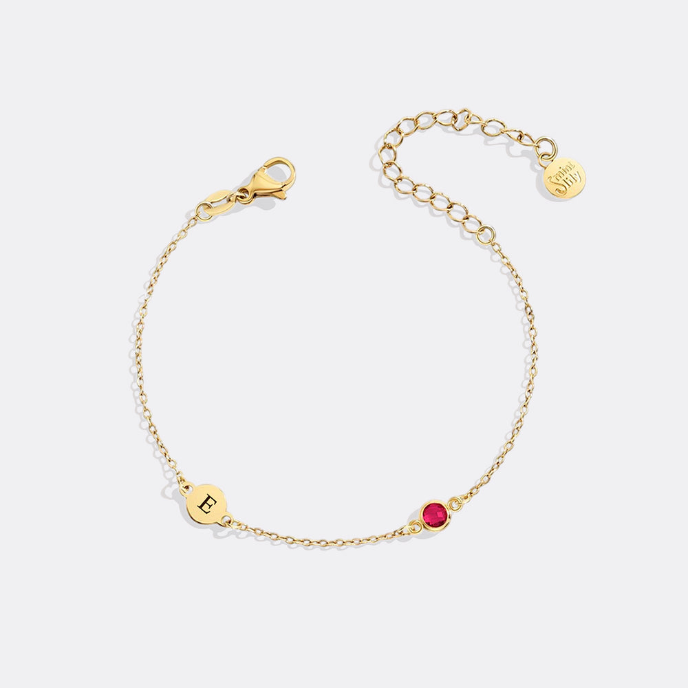 Gold bracelet with a red gemstone on a white background