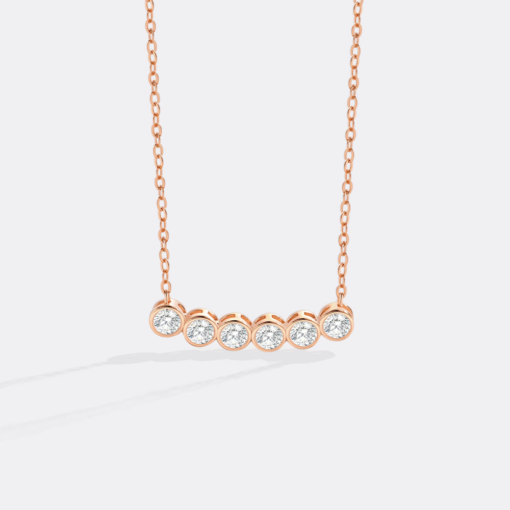 Rose gold necklace with five diamonds on a white background
