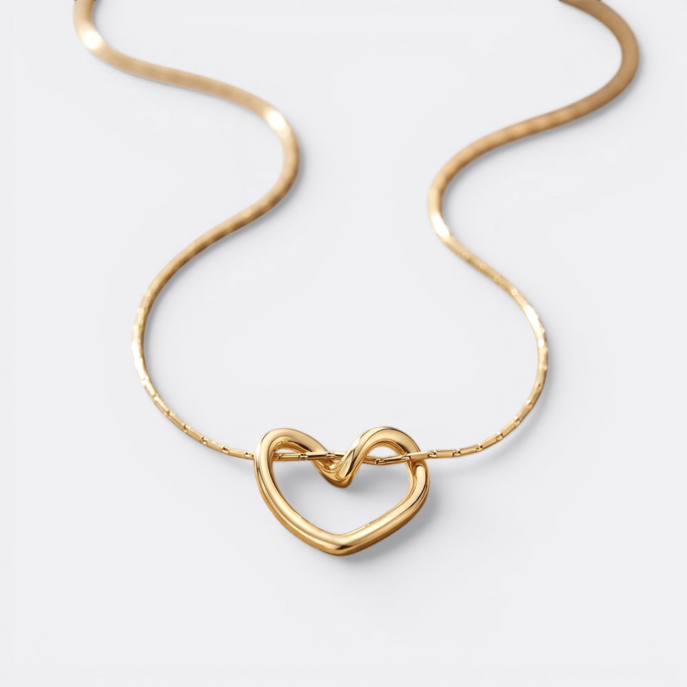 Gold heart-shaped necklace on a light gray background