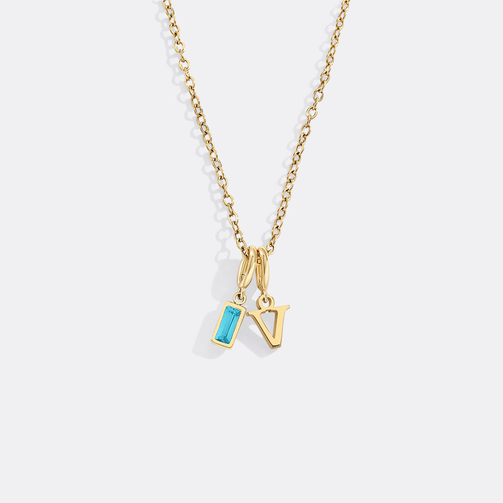 Gold necklace with a blue pendant and letter 'N' charm on a white background