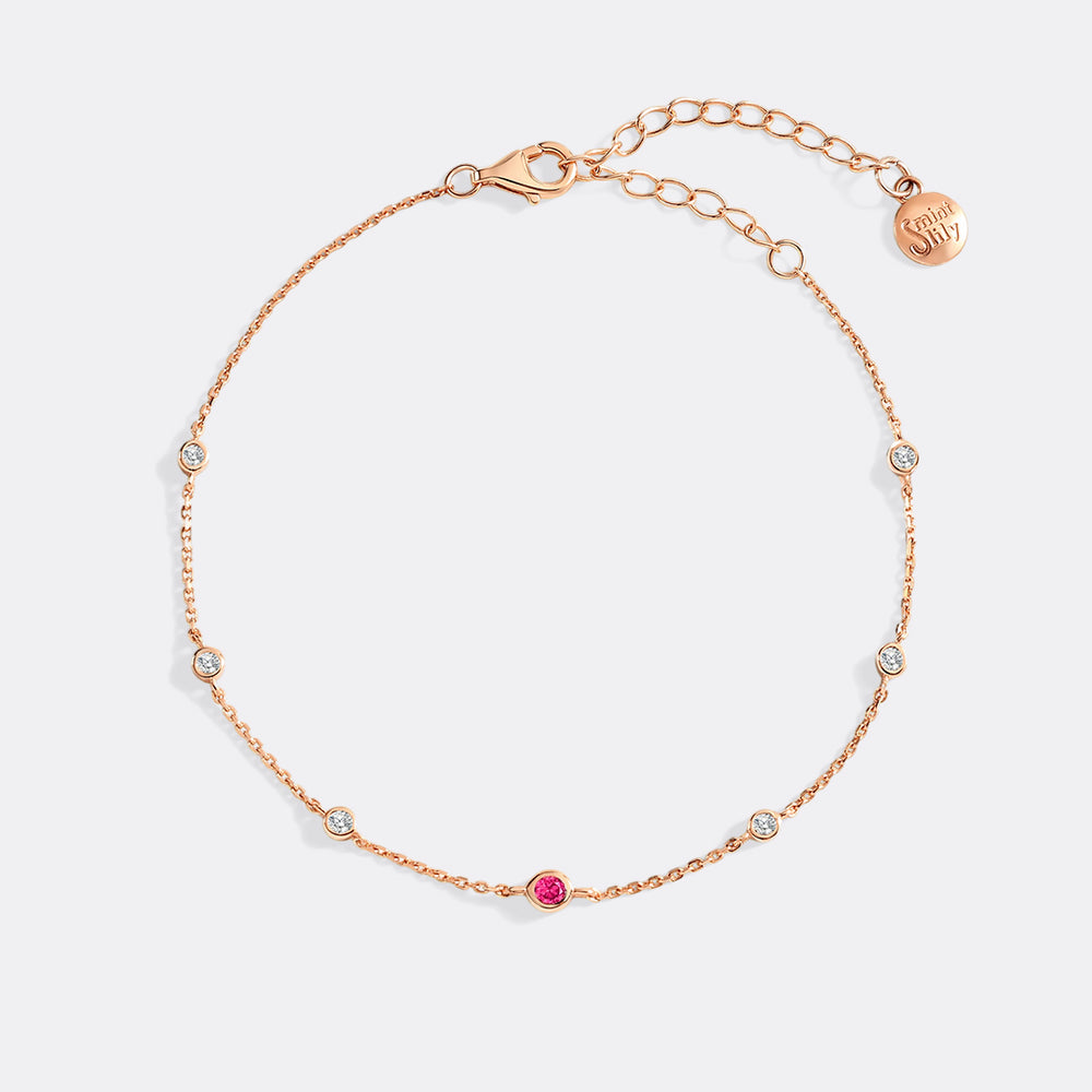 Rose gold bracelet with small diamonds and a pink gemstone on a light gray background