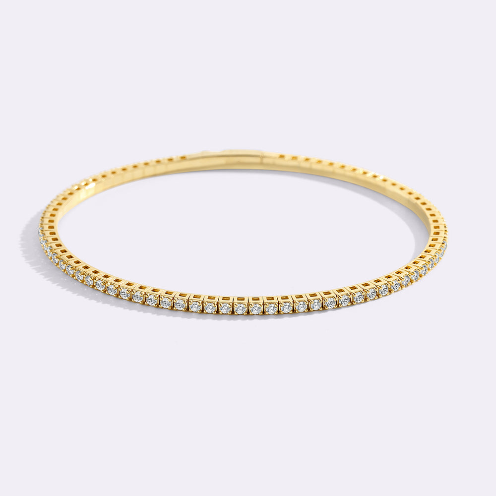 Gold bracelet with cubic zirconia gemstones on a light gray background