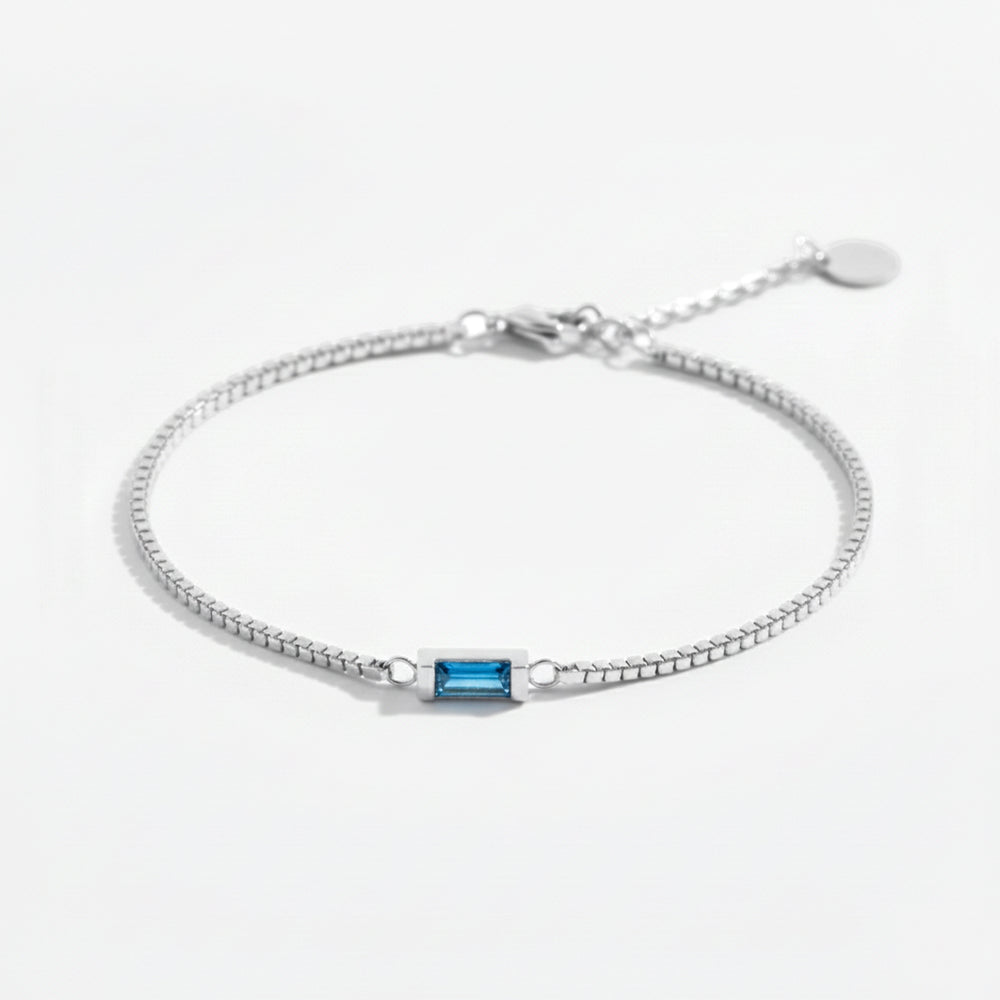 Silver bracelet with a blue gemstone on a white background