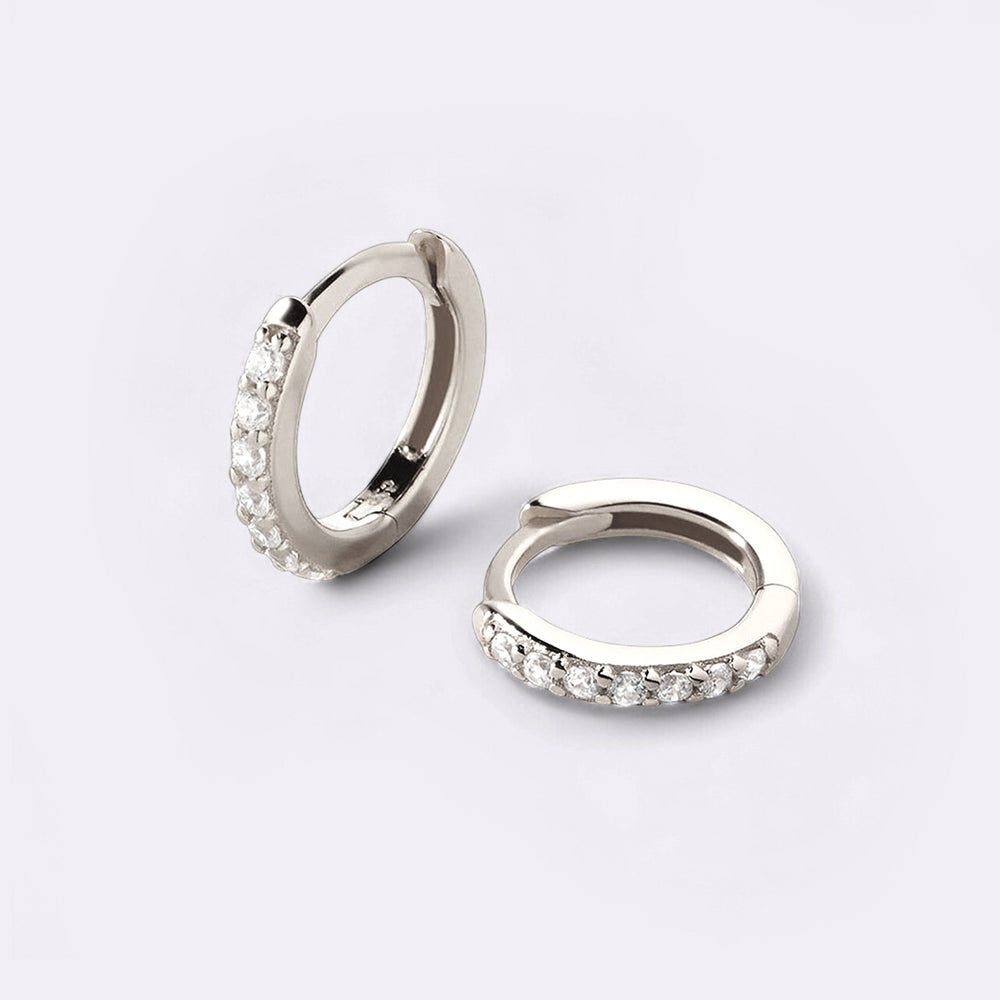Pair of silver hoop earrings with small stones on a light gray background