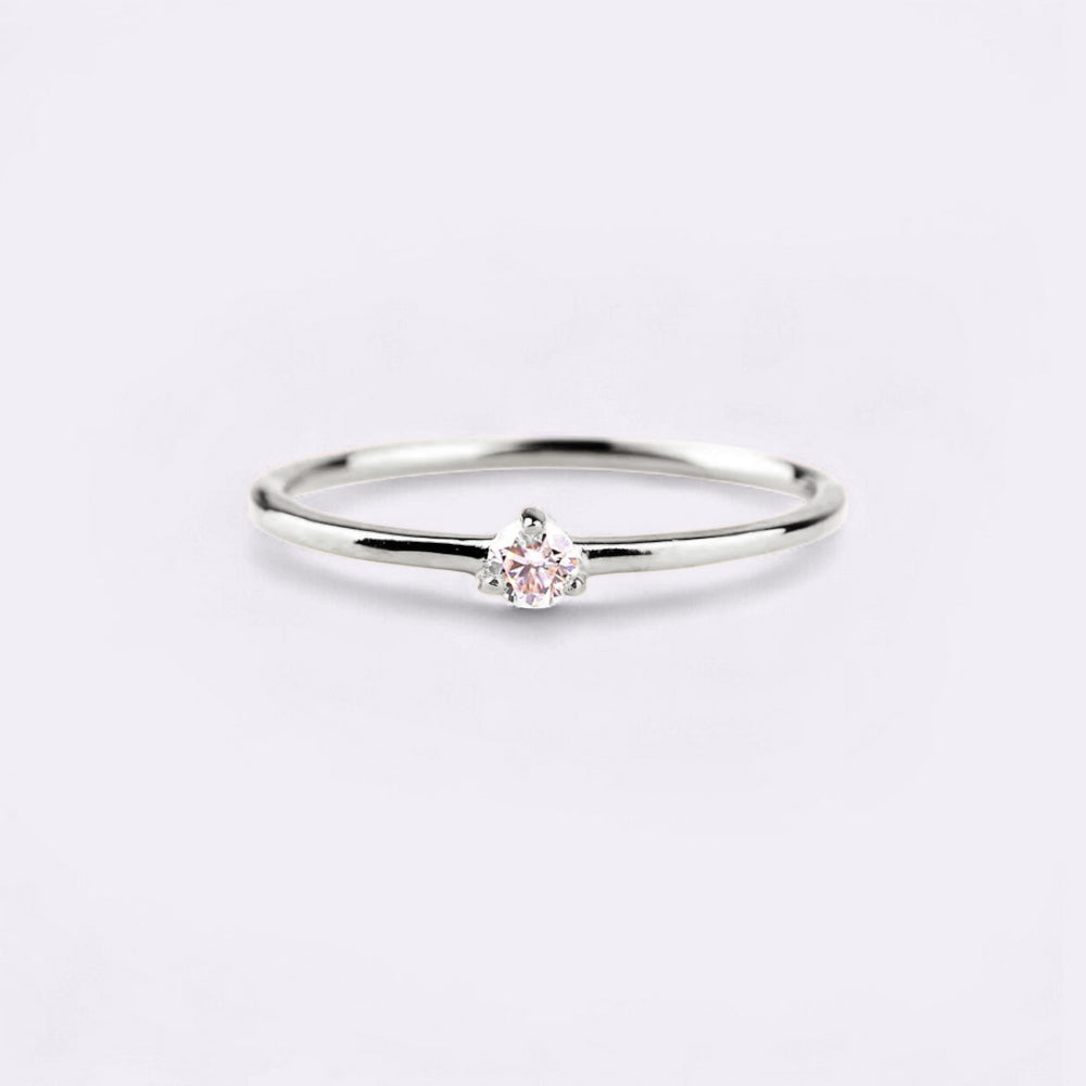 Silver ring with a small pink gemstone on a light gray background