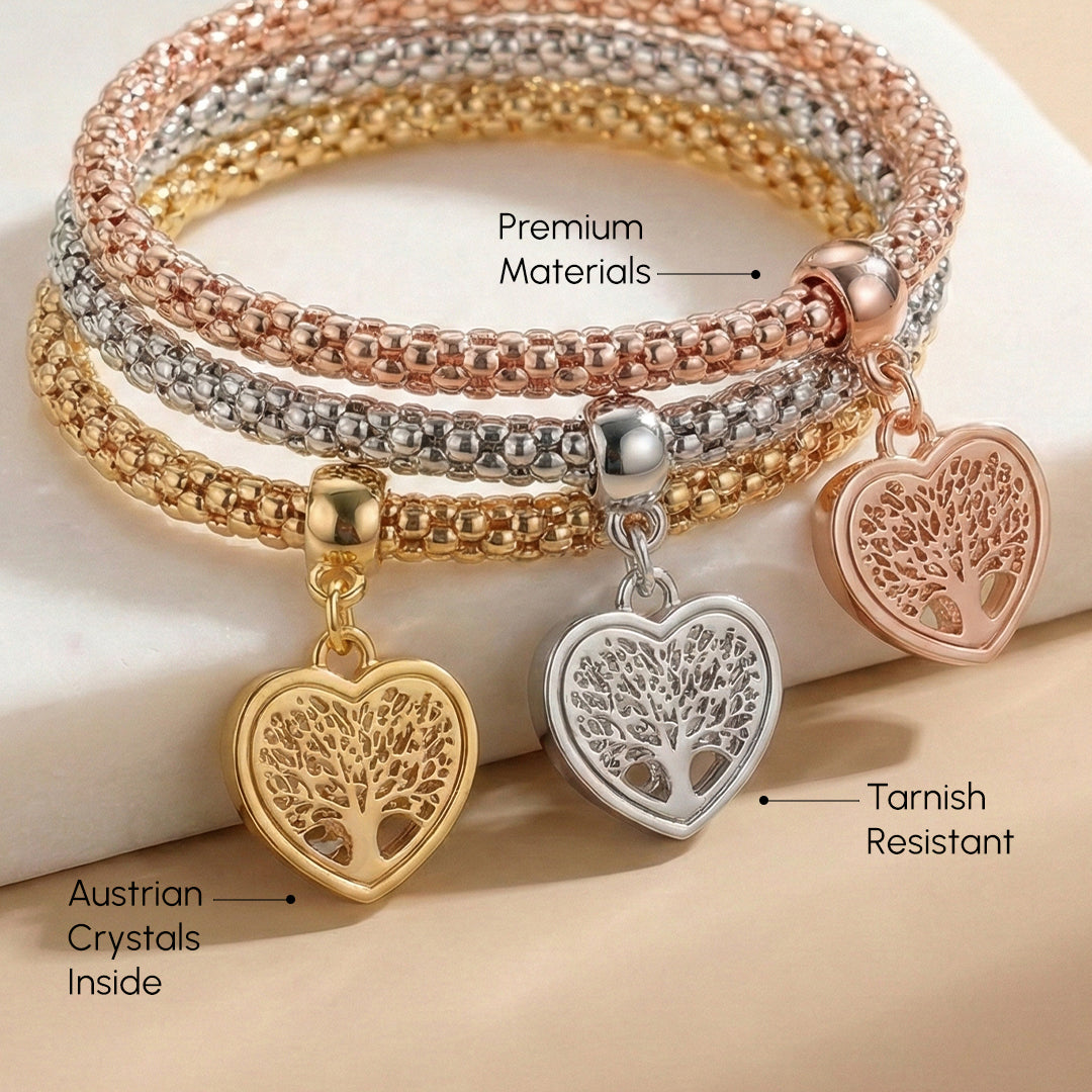 Stack of gold, silver, and rose gold bracelets with heart-shaped tree charms on a beige background.